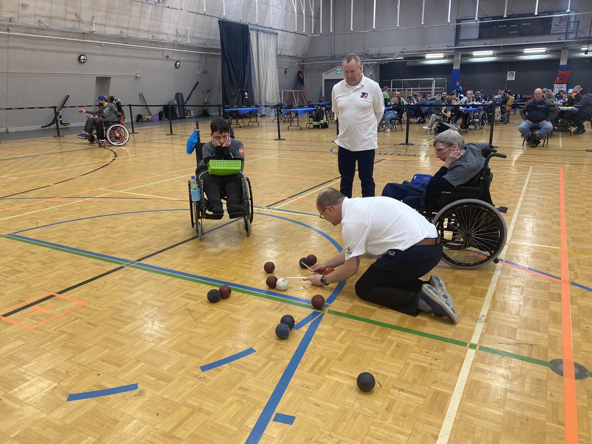 Arbitre de boccia sur le terrain en compagnie d'athlète de boccia et d'autres officiels